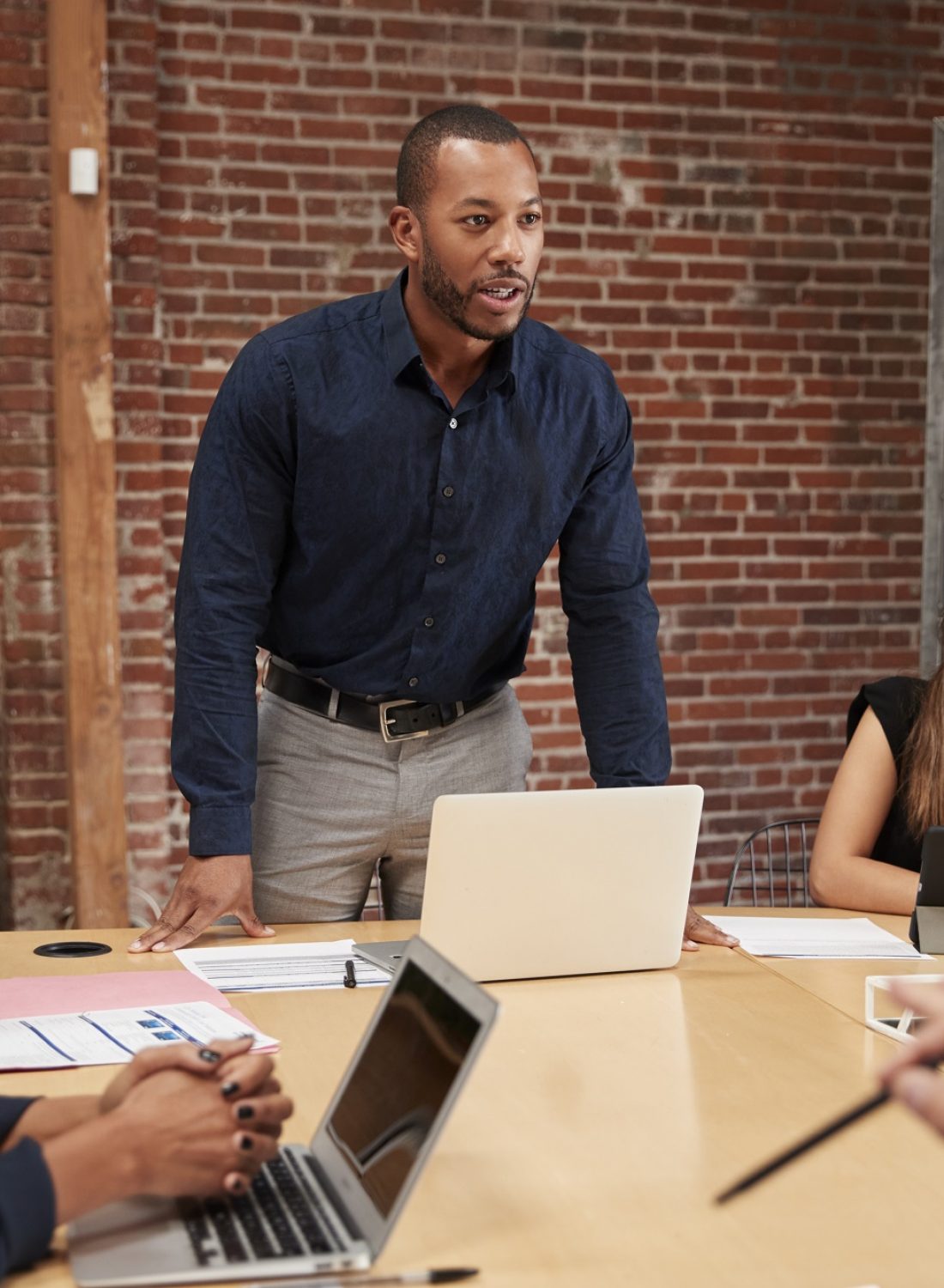 Businessman Standing And Leading Office Meeting Around Table